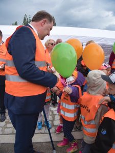 Prezydent Klimaszewski trzymający zielony balonik podczas rozmowy z jednym z przedszkolaków.
