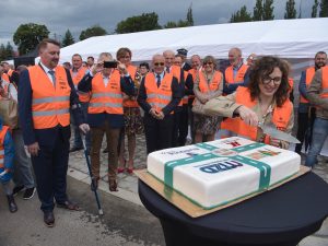 Pracownica Miejskiego Zarządu Dróg w Bielsku-Białej otoczona gośćmi przystępuje do krojenia okolicznościowego tortu.