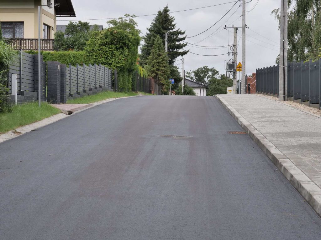 Ul. Falista. Widok na nową nawierzchnię asfaltową. Po prawej stronie nowy chodnik, z lewej odwodnienie jezdni.