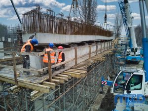 11. Ekipa budowlana podczas precyzyjnego montowania betonowego elementu wiaduktu.