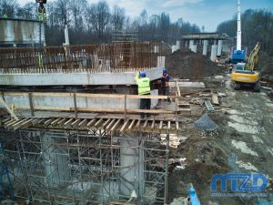 12. Ekipa budowlana podczas precyzyjnego montowania betonowego elementu wiaduktu.