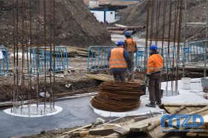 23. Trzech pracowników budowlanych stojących na betonowym fundamencie jednej z podpór wiaduktu.